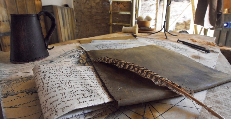 Props in the Elizabethan House on a table, including a jug, feather quill and writing